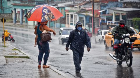 People walk under the rain in Havana on August 27, 2021, as Hurricane Ida passes through eastern Cuba.