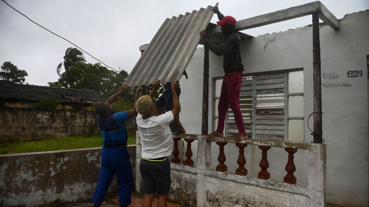 Men placed a corrugated metal sheet on the roof of a house under the rain in Batabano, Mayabeque province, about 60 km south of Havana, on August 27, 2021, as Hurricane Ida passed through eastern Cuba. 