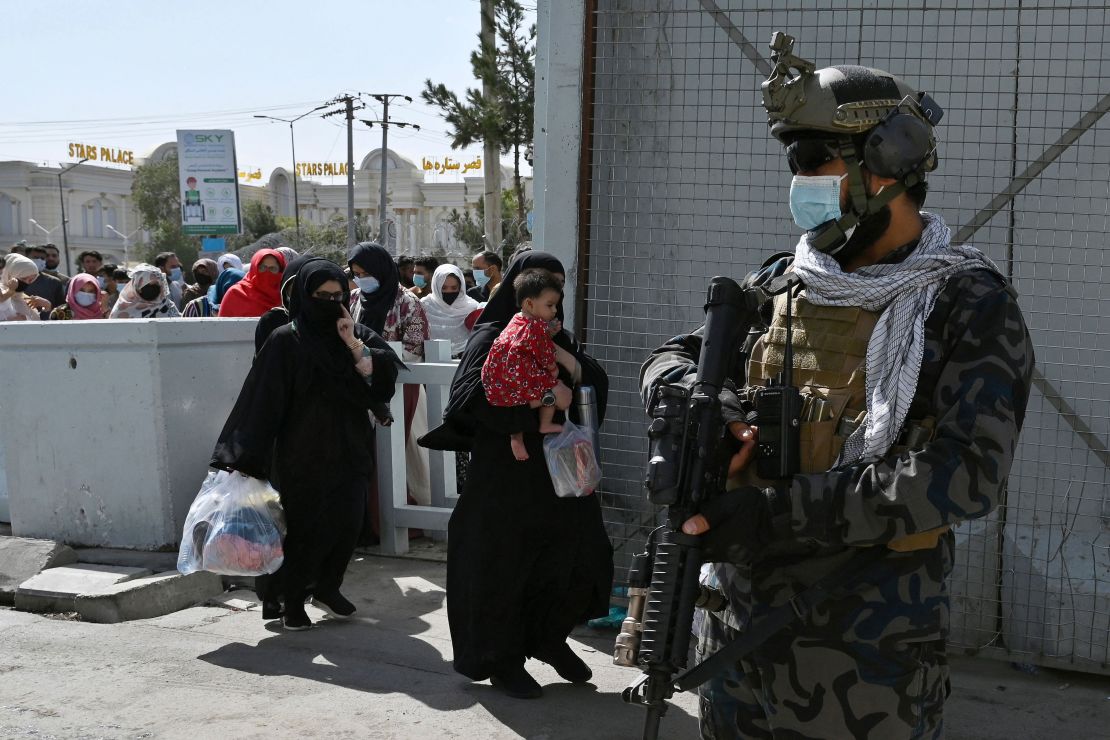 Taliban Badri fighters, a "special forces" unit, stand guard as Afghans walk through the main entrance gate of Kabul airport on Saturday.