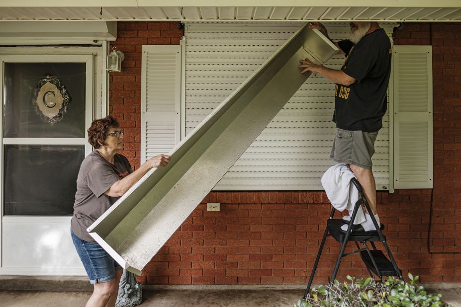 Clare and Joe Cermak work on putting storm shutters up on their home in Louisiana's St. Charles Parish on August 28.
