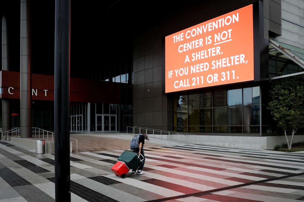 A man carrying his belongings walks past a sign outside the Ernest N. Morial Convention Center in New Orleans on August 29.