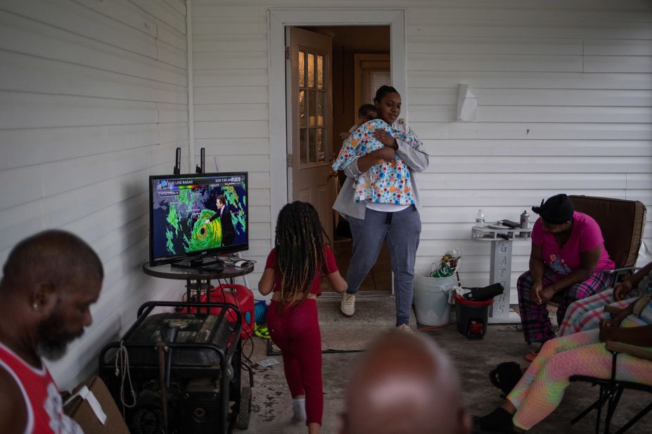 LaKeisha Verdin holds her 3-month-old son, Kevin, as she walks onto the front porch where her family was watching weather updates on the local news in Houma.