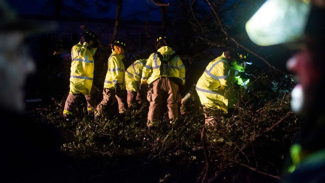 Firefighters cut through downed trees on a road in Bourg on August 29.