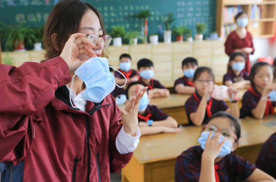 A primary school teacher shows her students how to properly wear a mask in Lianyungang city, eastern China's Jiangsu Province, on August 30, ahead of the official start of the new semester on September 1. On Friday, China's health authorities announced that the country's Delta variant outbreak has been "effectively brought under control."