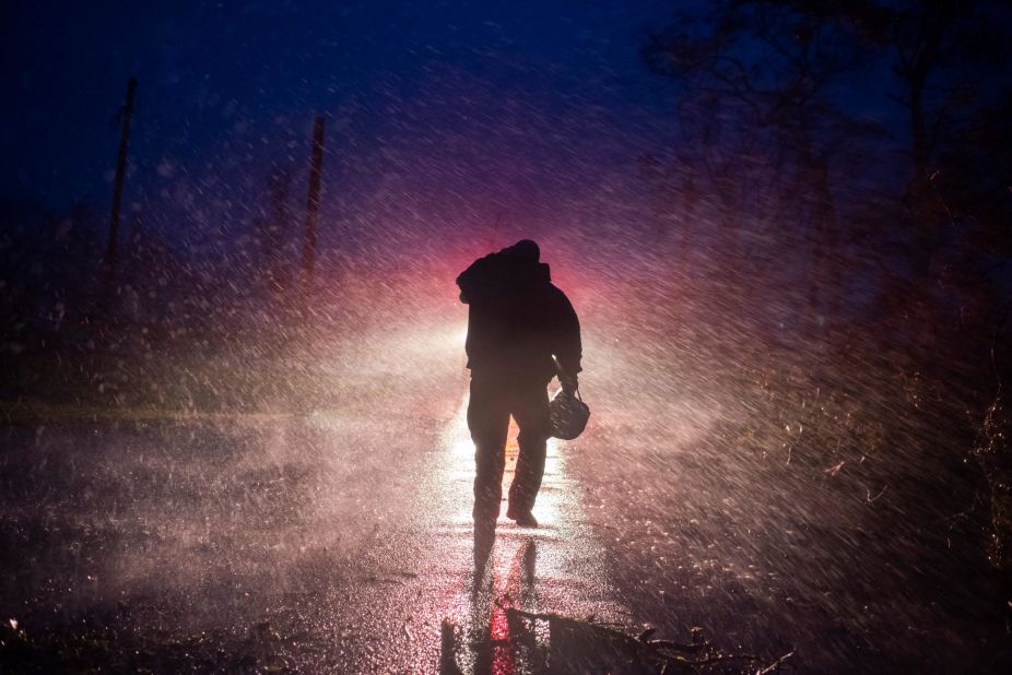 Montegut Fire Chief Toby Henry walks back to his fire truck in the rain as firefighters cut through trees on the road in Bourg, Louisiana, on August 29.