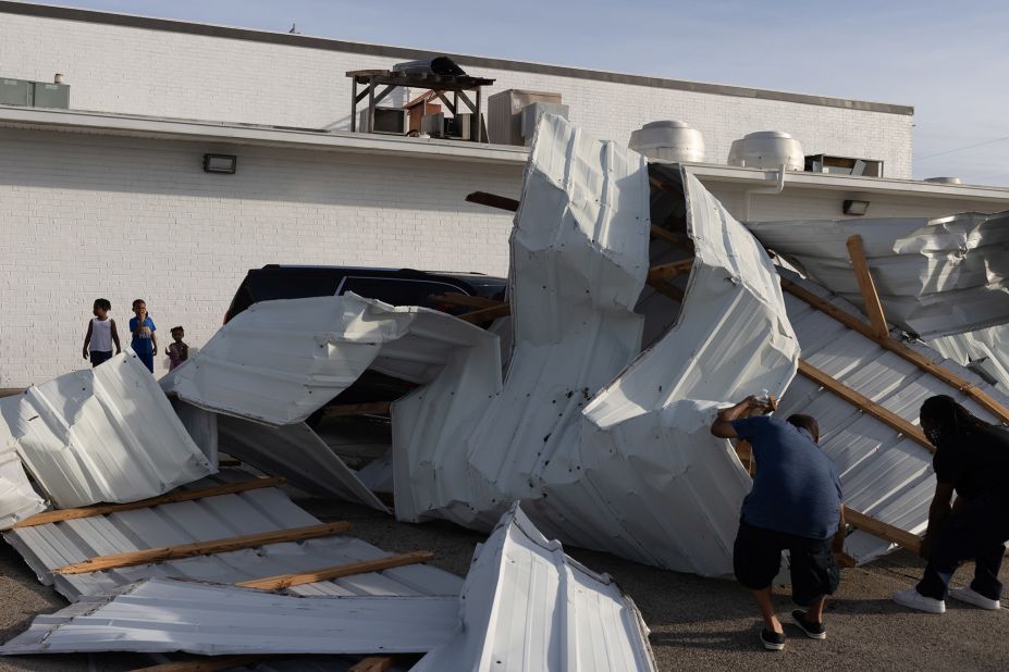 Siblings watch men assess damage outside a hotel in Houma on August 30.