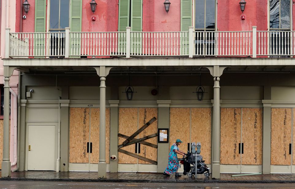 A woman pushes a stroller past a boarded-up building in the French Quarter of New Orleans on August 30.
