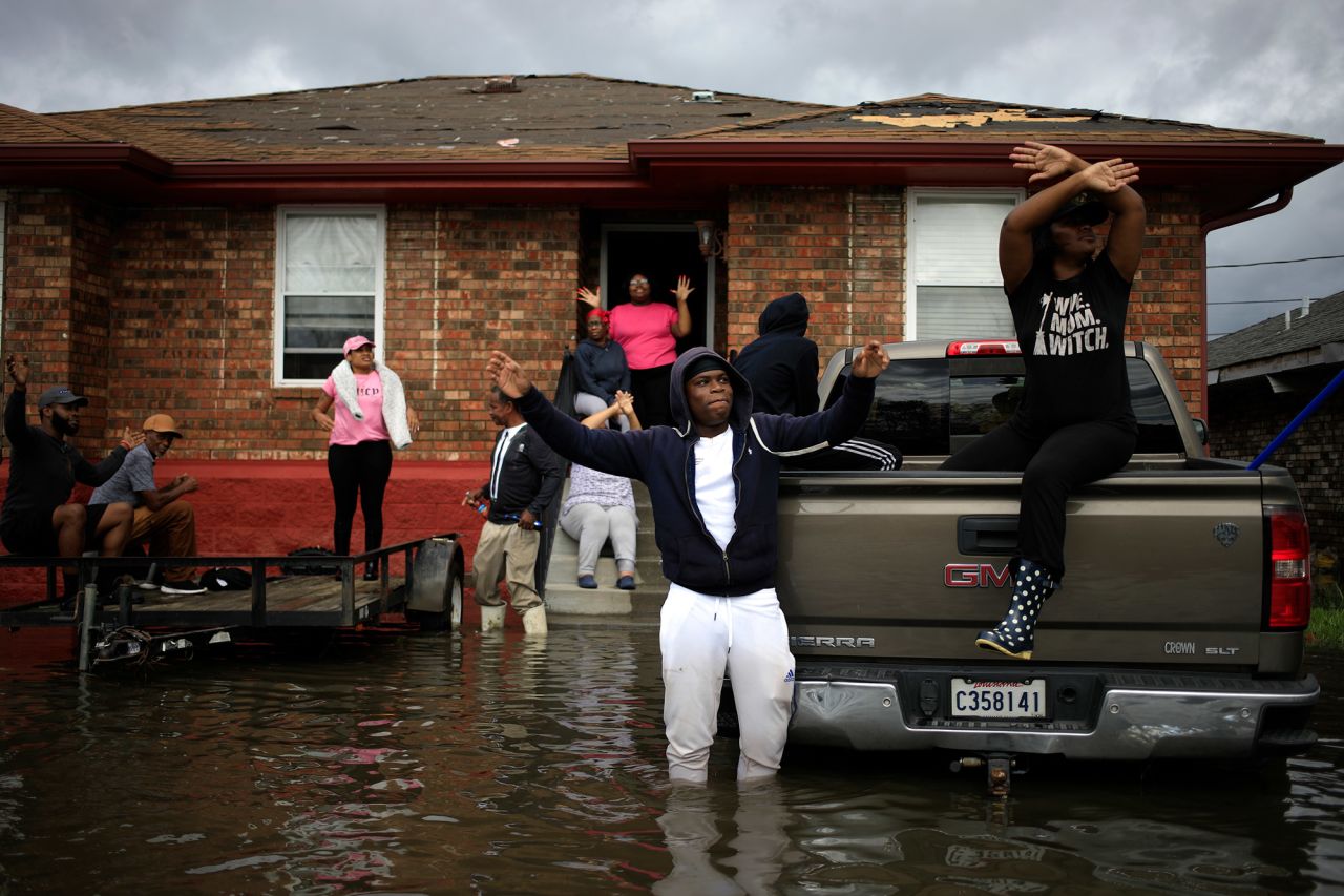 Residents wave at a US Coast Guard helicopter while waiting to be rescued from their flooded home in LaPlace on August 30.