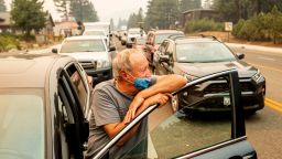 With the Caldor Fire approaching, Jim Mrazek stands outside his vehicle on Highway 50 as evacuee traffic stands still in South Lake Tahoe, Calif., on Monday, Aug. 30, 2021. Mrazek, who was stopped in that spot for more than an hour, said he was considering taking his boat into the lake instead of trying to drive out. (AP Photo/Noah Berger)