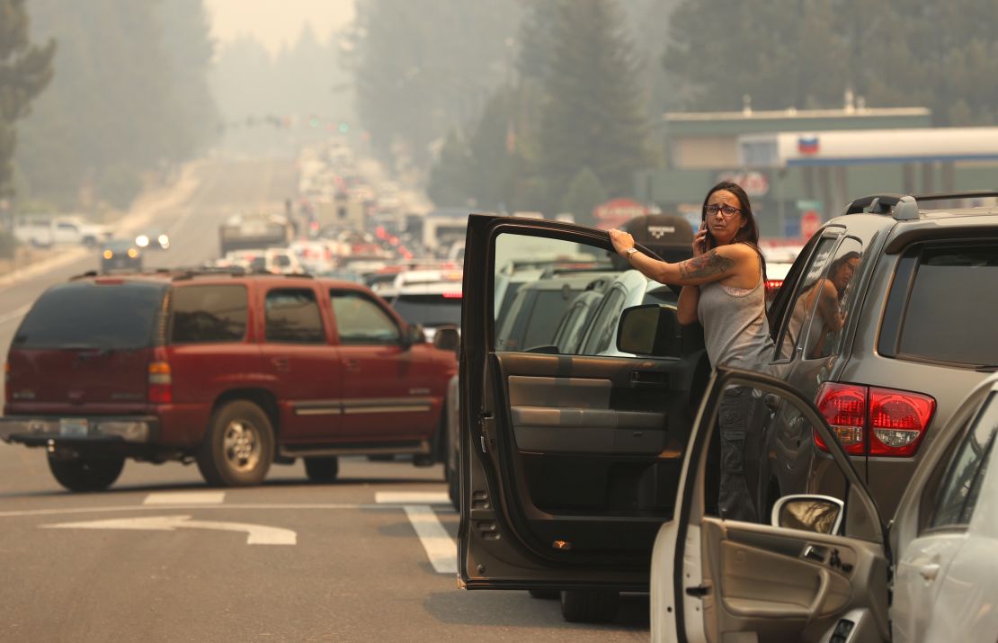 A woman talks on her phone while stopped in heavy traffic on Hwy 50 as people evacuate ahead of the Caldor Fire on August 30, 2021, in South Lake Tahoe, California. 