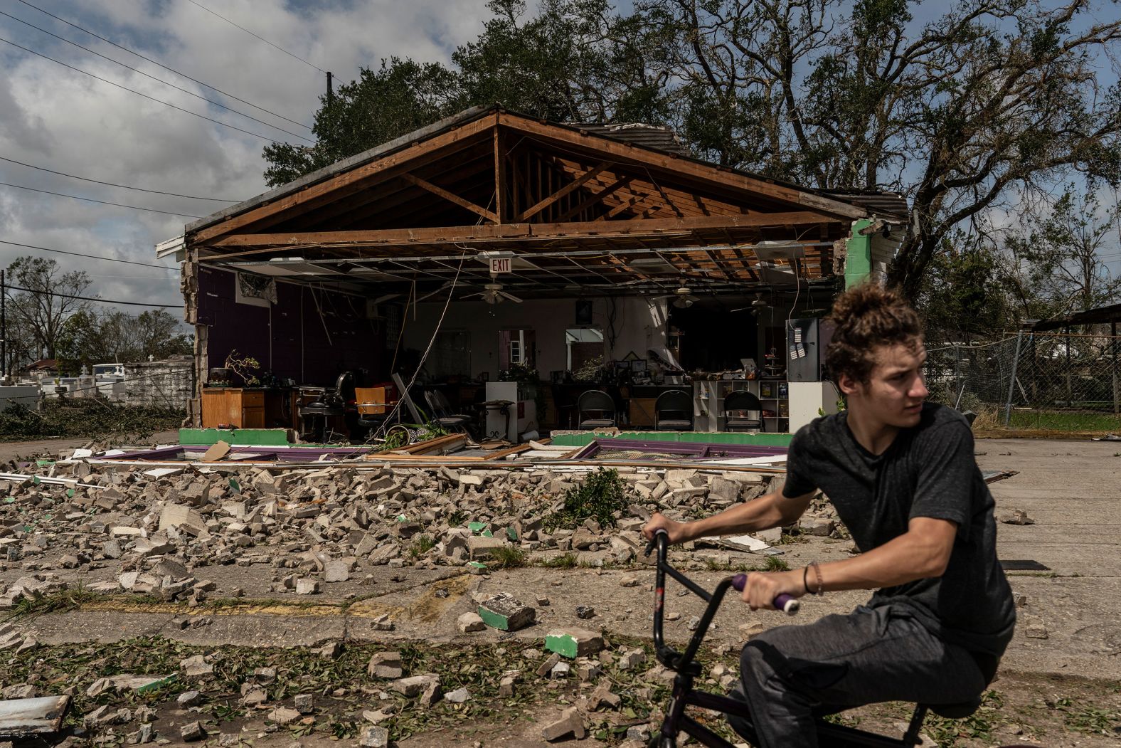 A man rides a bicycle in front of a damaged building in Houma on August 30.