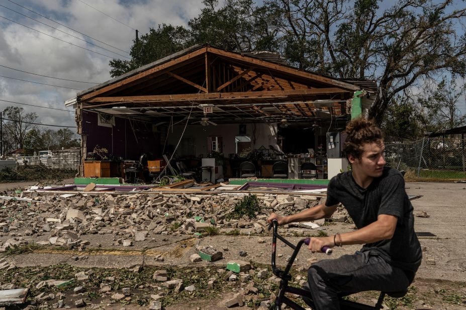 A man rides a bicycle in front of a damaged building in Houma on August 30.