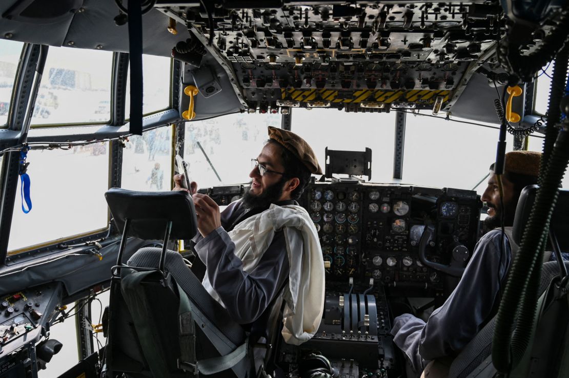 Taliban fighters sit in the cockpit of an Afghan Air Force aircraft at the airport in Kabul on August 31.