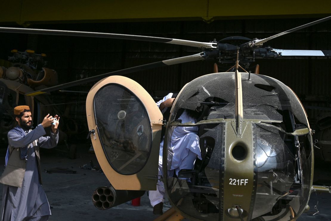 A Taliban fighter takes a picture of a damaged Afghan Air Force helicopter near a hangar at the airport.