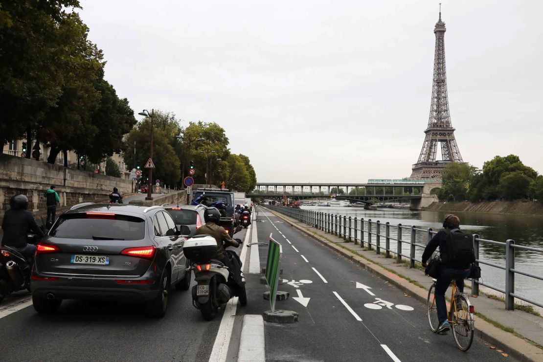 A cyclists rides by congested traffic along the Seine River in Paris.