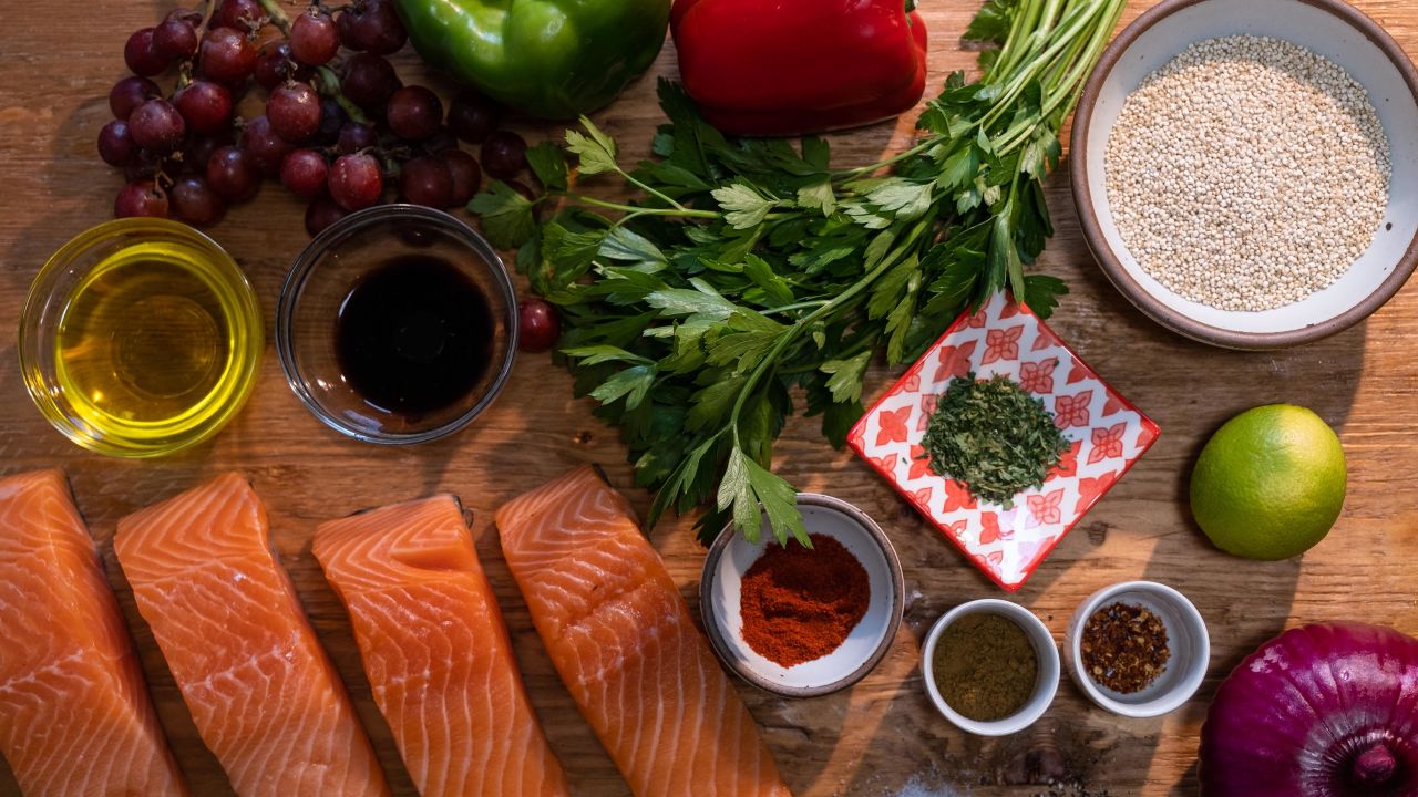 Mediterranean-inspired grocery staples include heart-healthy fish like salmon, fresh fruits and veggies, whole grains, spices, and extra-virgin olive oil.