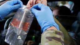 In this file photo, a driver hands over his testing kit to an Illinois National Guard soldier at a testing facility in Waukegan, Ill., Saturday, May 2, 2020.