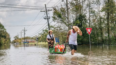 Residents move gas cans through a flooded neighborhood on Tuesday in Barataria, Louisiana.