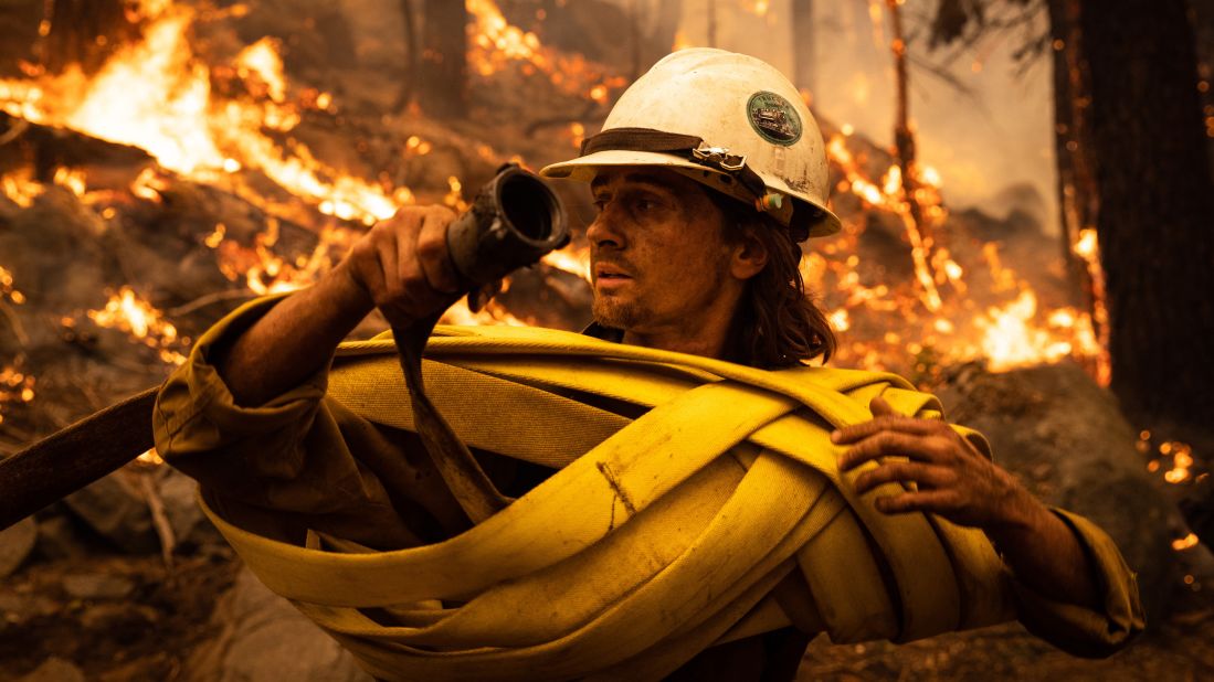 A firefighter winds up hose at a spot fire near Meyers, California, on August 30.