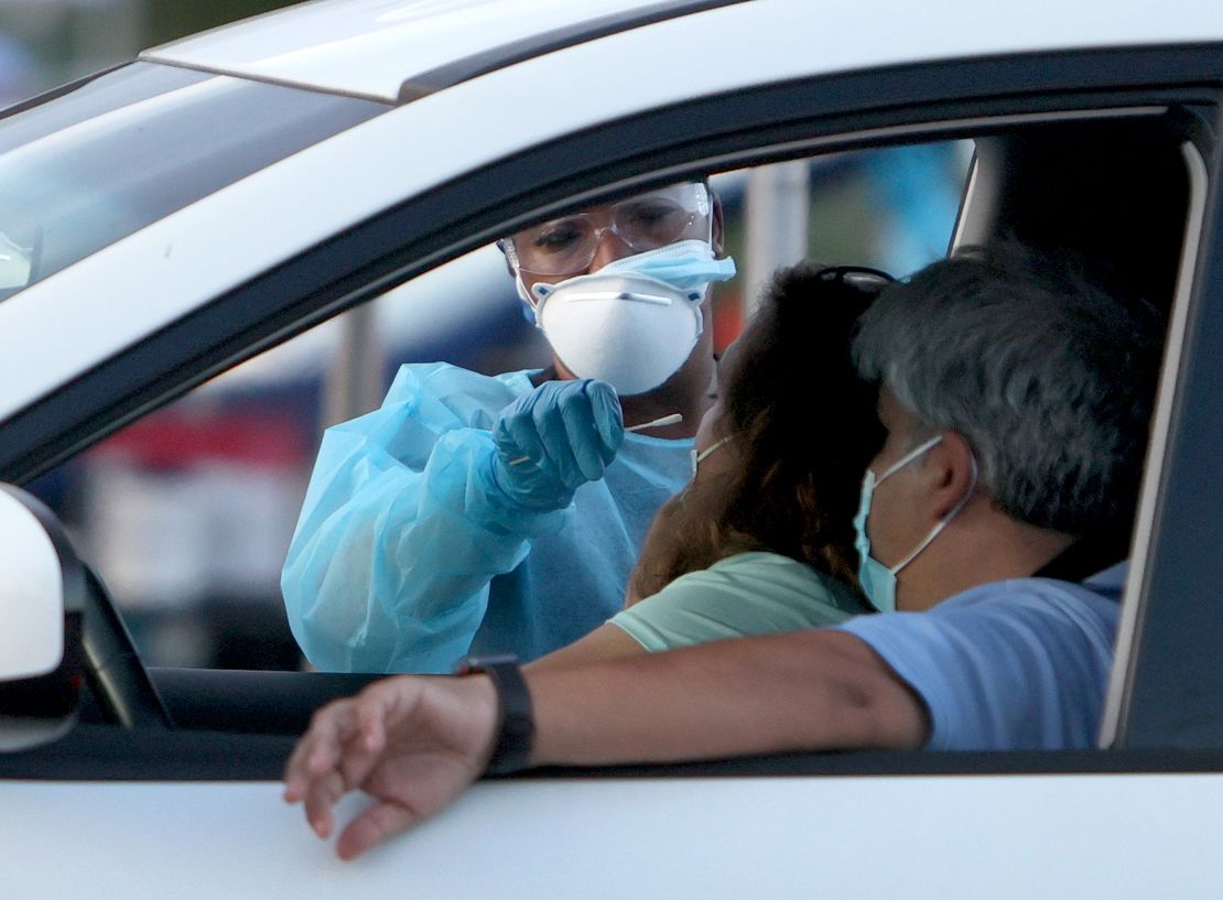 A health care worker at a 24-hour drive-thru site set up by Miami-Dade and Nomi Health in Tropical Park administers a Covid-19 test on Monday in Miami. 