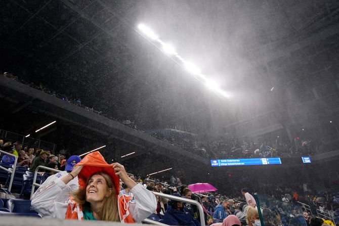 A tennis fan covers herself from rain as she attends a match at the US Open in New York on September 1. A second-round singles match between Kevin Anderson and Diego Schwartzman was halted early in the second set as <a href="index.php?page=&url=https%3A%2F%2Fwww.cnn.com%2F2021%2F09%2F02%2Ftennis%2Fus-open-tennis-flooding-spt-intl%2Findex.html" target="_blank">water came through multiple openings of the roof on Louis Armstrong Stadium.</a> The match was moved to the Arthur Ashe Stadium and completed just after 1 a.m. Thursday.