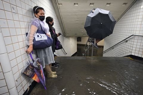 People stand inside a subway station in New York City as water runs past their feet on Wednesday, September 1.