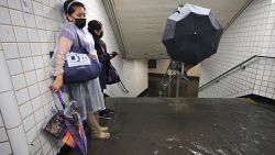 People stand inside a subway station as water runs past their feet during flash flooding caused by storm Ida in New York.