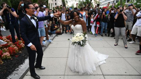 Waizeru Johnson holds her new husband's hand as she passes a group of people celebrating the Juneteenth holiday at Black Lives Matter Plaza in Washington on June 19, 2021. 
