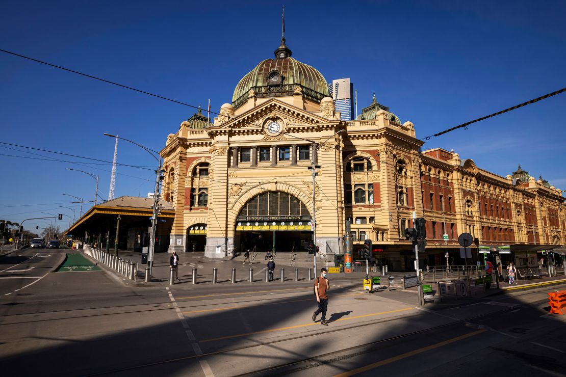 People are seen crossing a quiet Flinders Street on September 1, 2021 in Melbourne, Australia.