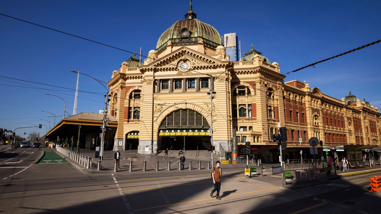 People are seen crossing a quiet Flinders Street on September 1, 2021 in Melbourne, Australia.