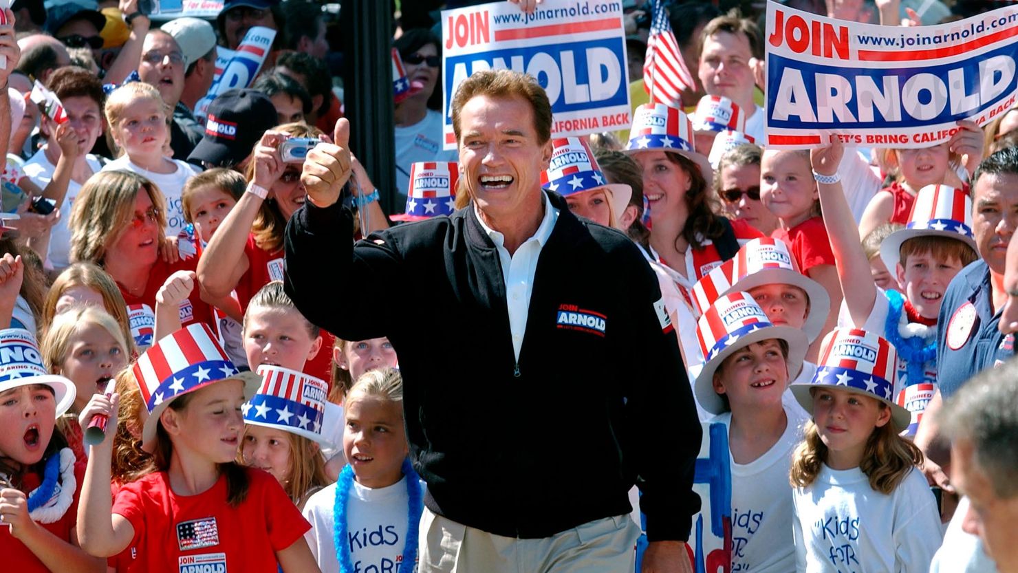 In this October 2003 photo, then-Republican candidate for California governor Arnold Schwarzenegger walks up the steps to the state Capitol surrounded by children and waving to supporters during a campaign rally in Sacramento.