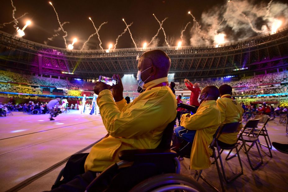Athletes take photos as fireworks light up the sky above the National Stadium during the closing ceremony.
