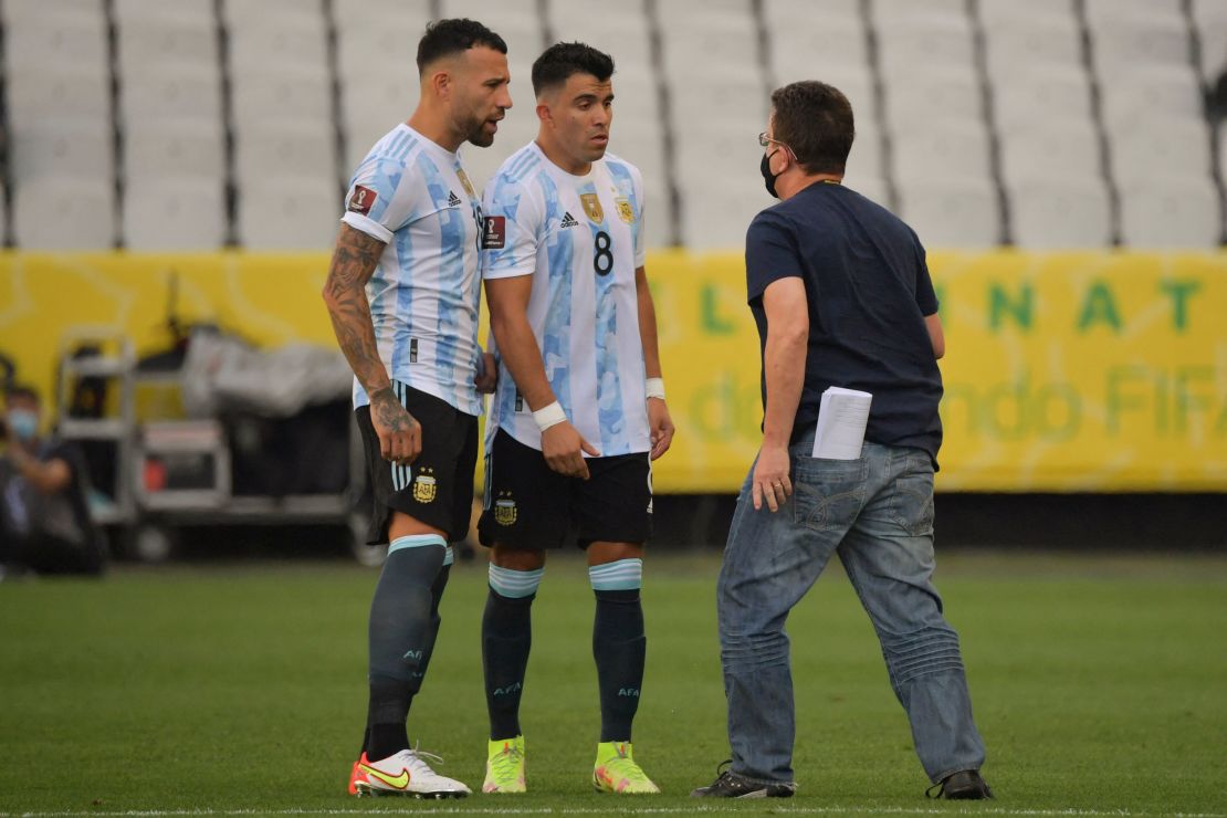 An employee of Brazil's National Health Surveillance Agency (Anvisa) argues with Argentina's Nicolas Otamendi (L) and Marcos Acuna.