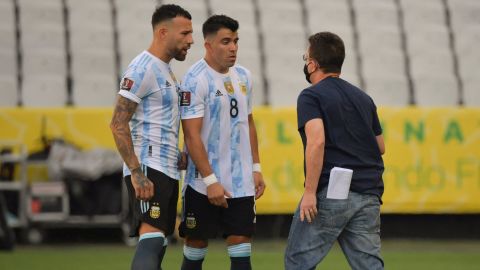 An employee of Brazil's National Health Surveillance Agency (Anvisa) argues with Argentina's Nicolas Otamendi (L) and Marcos Acuna.