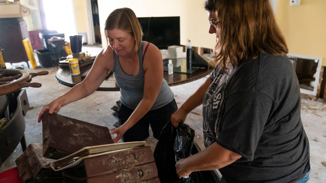 Michelle Smith, left, and her sister Cassie Falgoust throw out water-damaged family photo albums.
