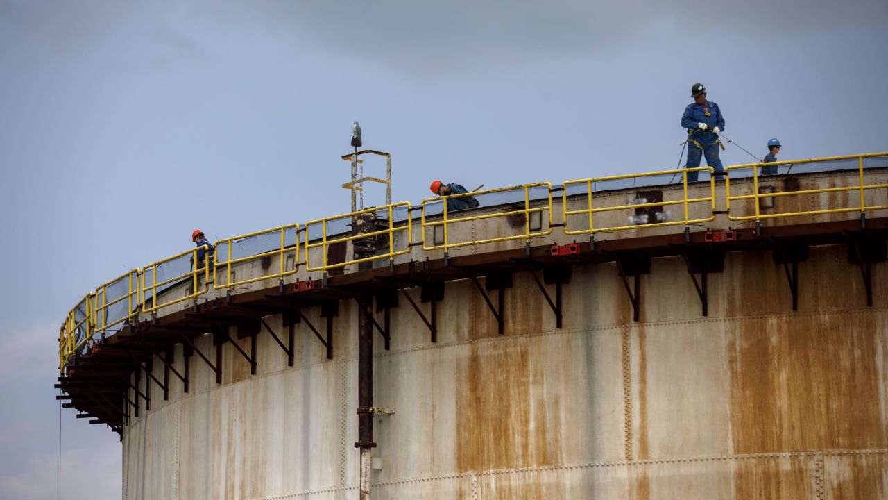 Workers stand atop a storage tank at an Imperial Oil Ltd. refinery near the Enbridge Line 5 pipeline in Sarnia, Ontario, Canada.