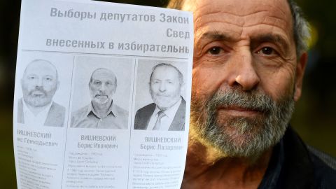 Russian politician Boris Vishnevsky poses with a photo of himself and two of his opponents in the St. Petersburg legislative elections.