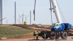 Workers stand next to a crane at Avangrid Renewables La Joya wind farm under construction in Encino, New Mexico, on Aug. 5, 2020. 