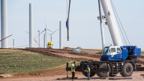 Workers stand next to a crane at Avangrid Renewables La Joya wind farm under construction in Encino, New Mexico, in 2020.