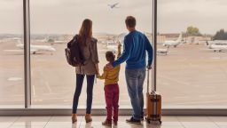 underscored family in airport terminal watching plane in sky