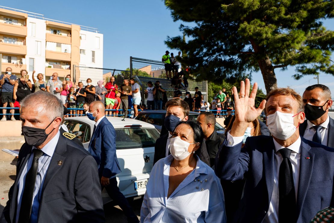 President Emmanuel Macron waves to locals in the Bassens district next to Marseille's Mayor Benoit Payan (center) during a visit to the southern port city on September 1, 2021.