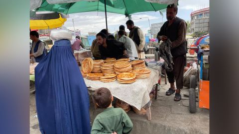A woman in a blue burqa buys naan bread in the Kabul bazar.
