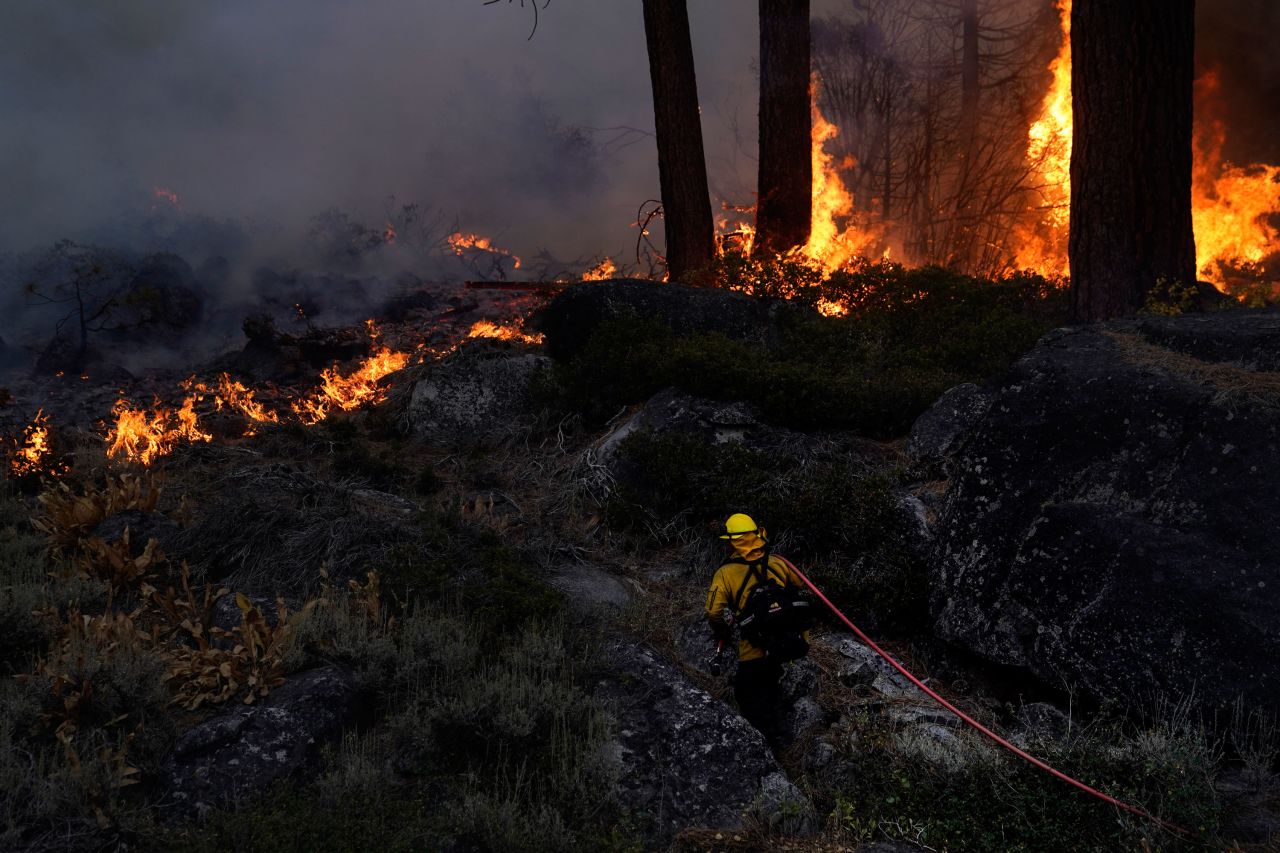 A firefighter carries a water hose toward a spot fire burning along Highway 89 near South Lake Tahoe, California, on Thursday, September 2. The governors of California and Nevada <a href="https://www.cnn.com/2021/08/31/weather/western-wildfires-tuesday/index.html" target="_blank">declared states of emergency</a> as the fast-moving Caldor Fire prompted officials to tell everyone to evacuate South Lake Tahoe.
