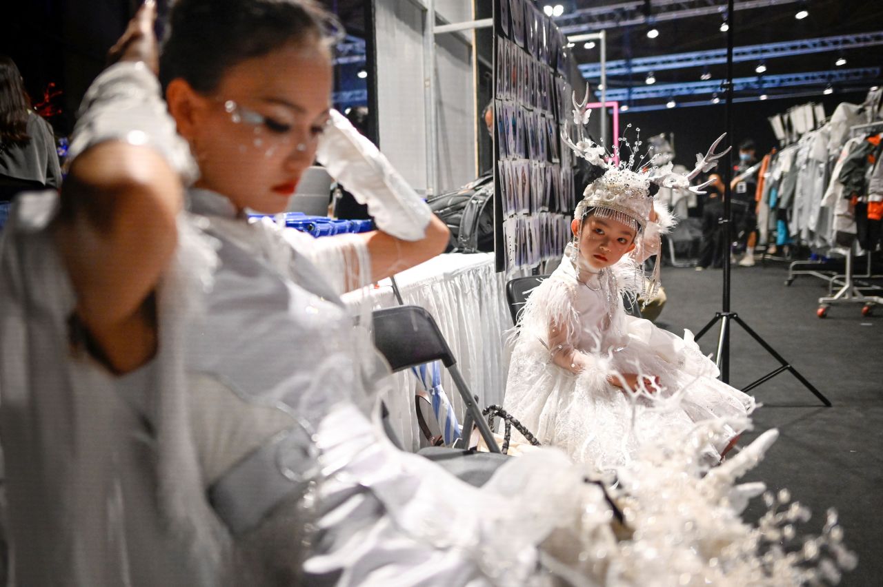 A child looks at a model as they prepare backstage at a Jingyi Jin fashion show in Beijing on Sunday, September 5.