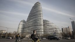 Commuters ride bicycles past commercial buildings at the Soho China Ltd. Wangjing Soho project in Beijing, China, on Friday, Nov. 25, 2016. 
