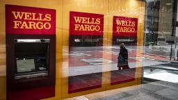 A person wearing a protective mask is reflected in the window of a temporarily closed Wells Fargo & Co. Bank branch in New York, U.S., on Friday, April 10, 2020. 