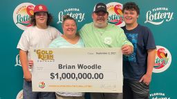 Auto repair shop owner Brian Woodle poses with a check after winning $1 million from a scratch-off Florida Lottery game.