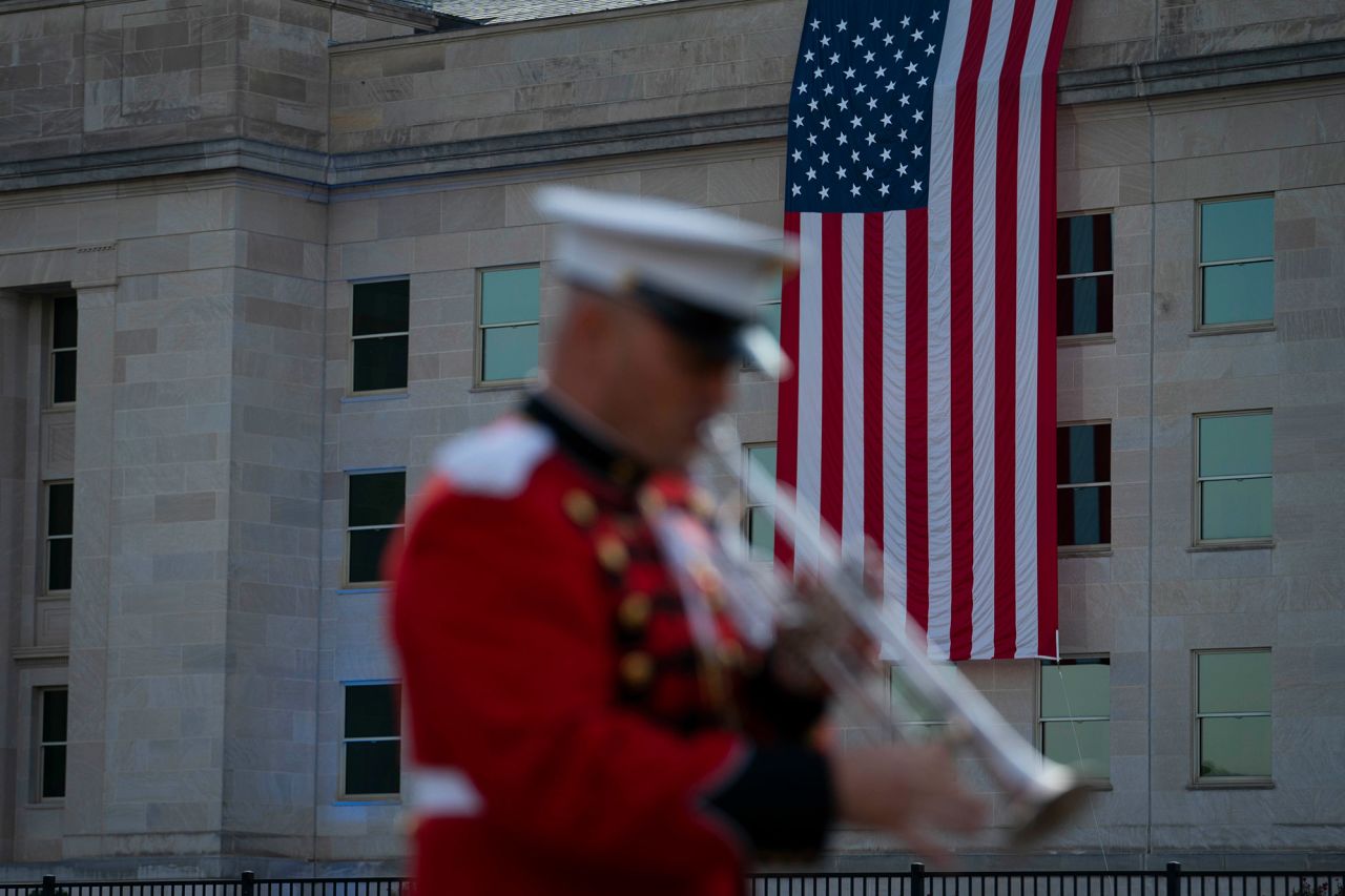 A musician practices ahead of a ceremony Saturday outside the Pentagon in Arlington, Virginia. The American flag is draped over the site of impact where the hijacked plane crashed into the Pentagon, killing 184 people.