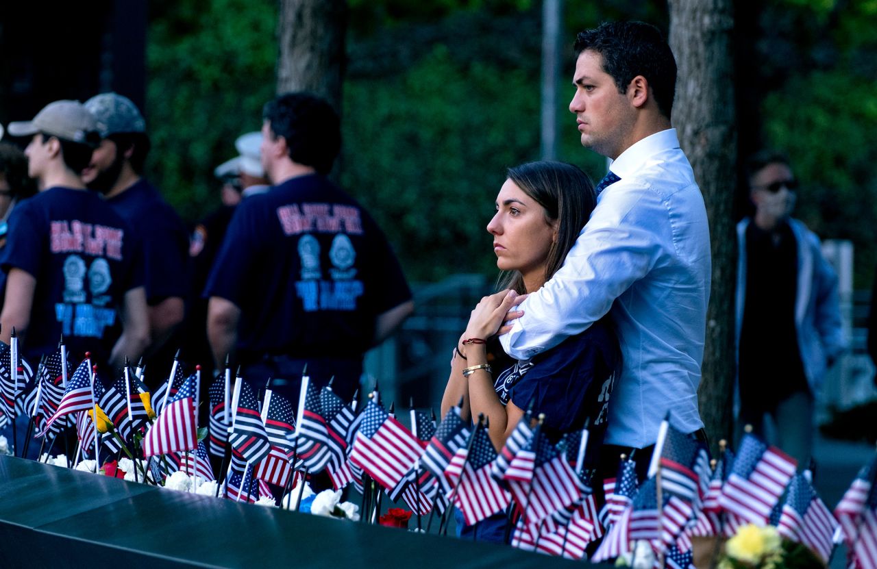 Katie Mascali is comforted by her fiance, Andre Jabban, as they stand near the name of her father, Joseph Mascali, during the ceremony in New York.