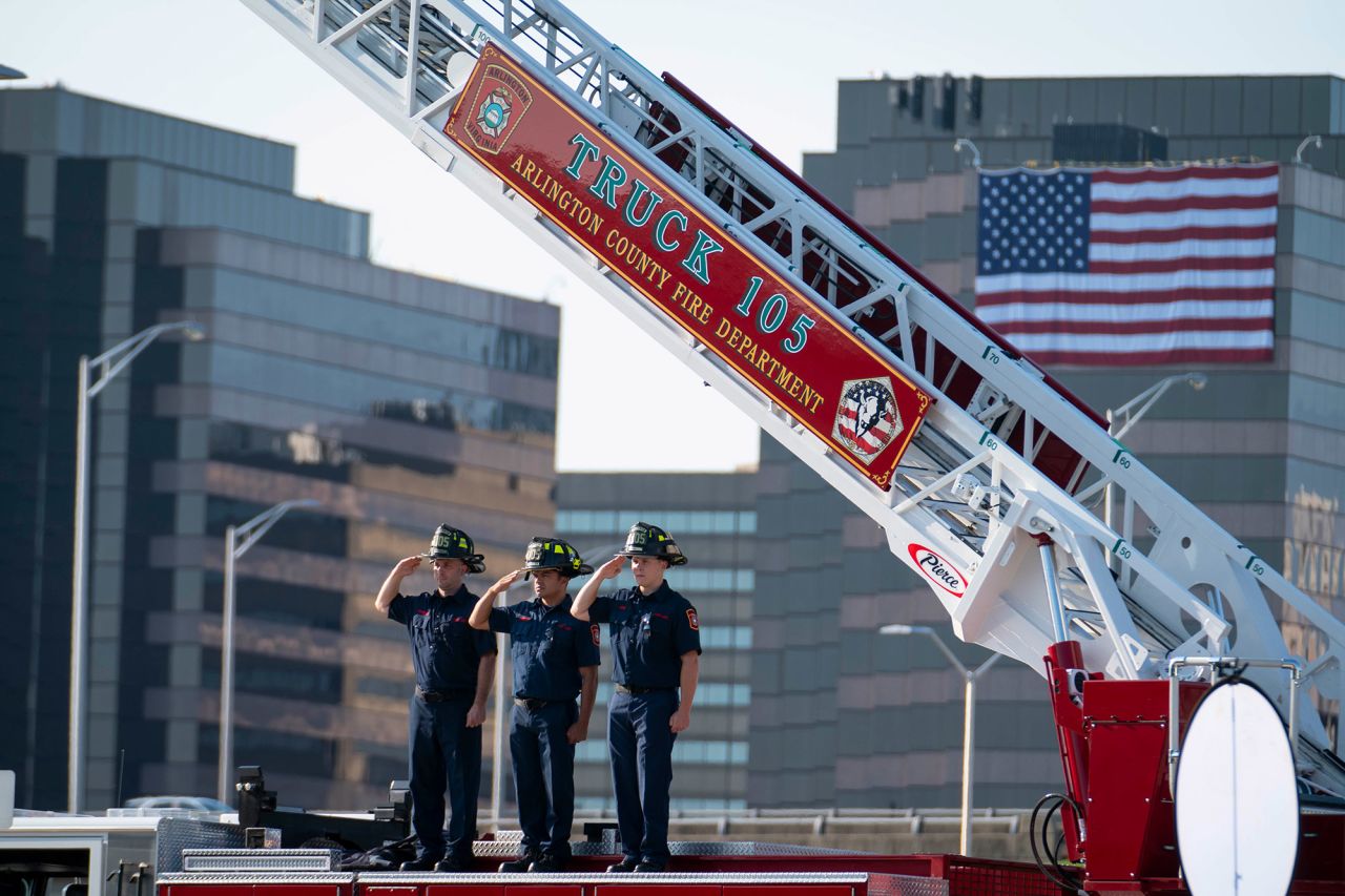 Firefighters salute on top of a firetruck during the ceremony at the Pentagon.
